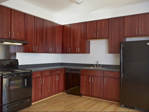 A kitchen with wooden cabinets and a black refrigerator.