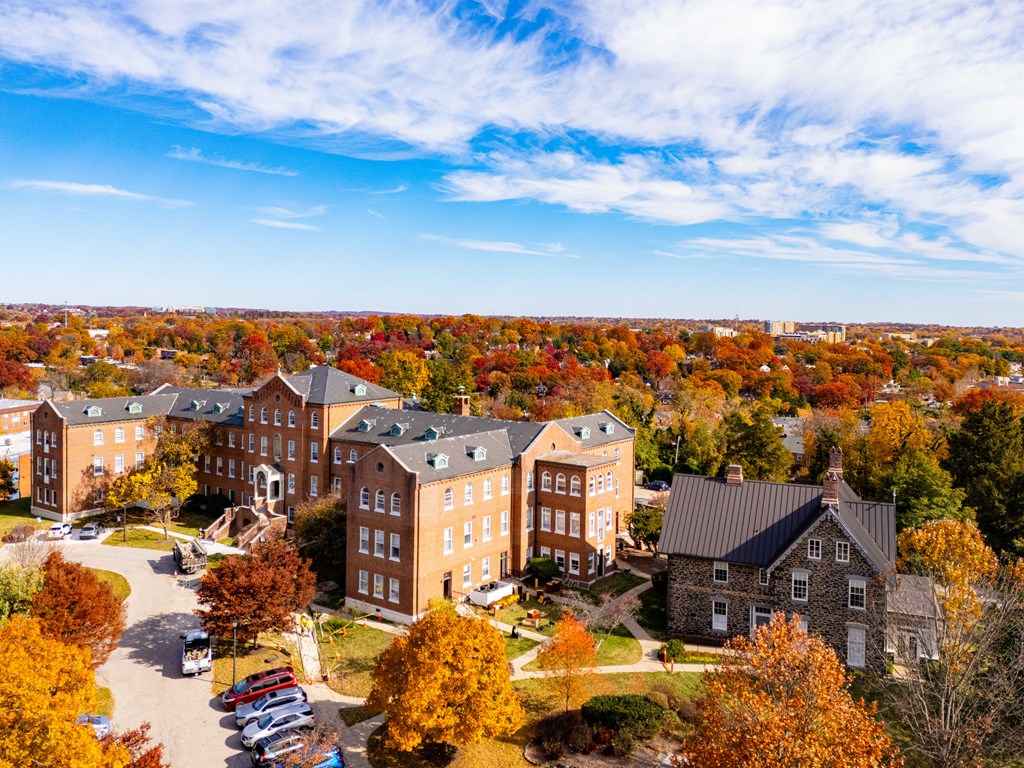 A large building complex surrounded by trees with autumn leaves.