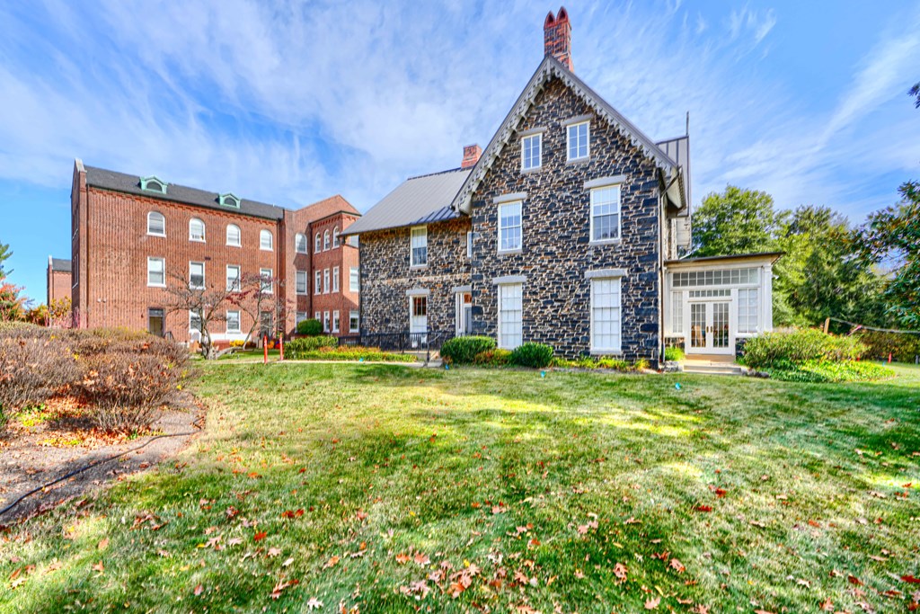 A stone house with a red brick building in the background.