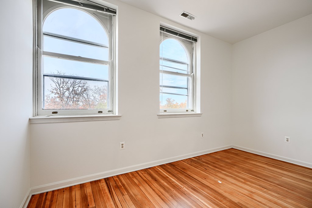A room with wooden floors and two windows.