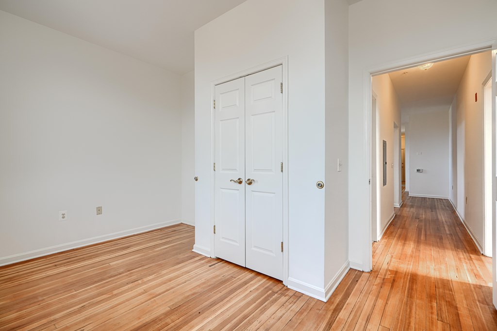 A room with a white door and wooden flooring.