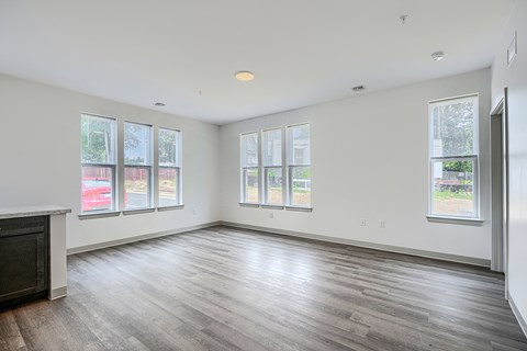 A large empty room with wooden floors and windows.