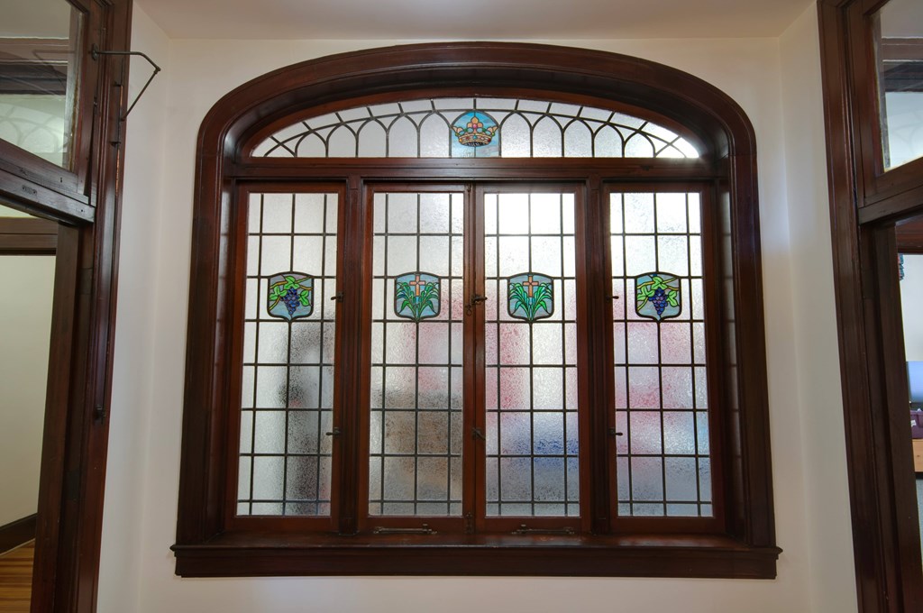 A stained glass window with a wooden frame and a white background.