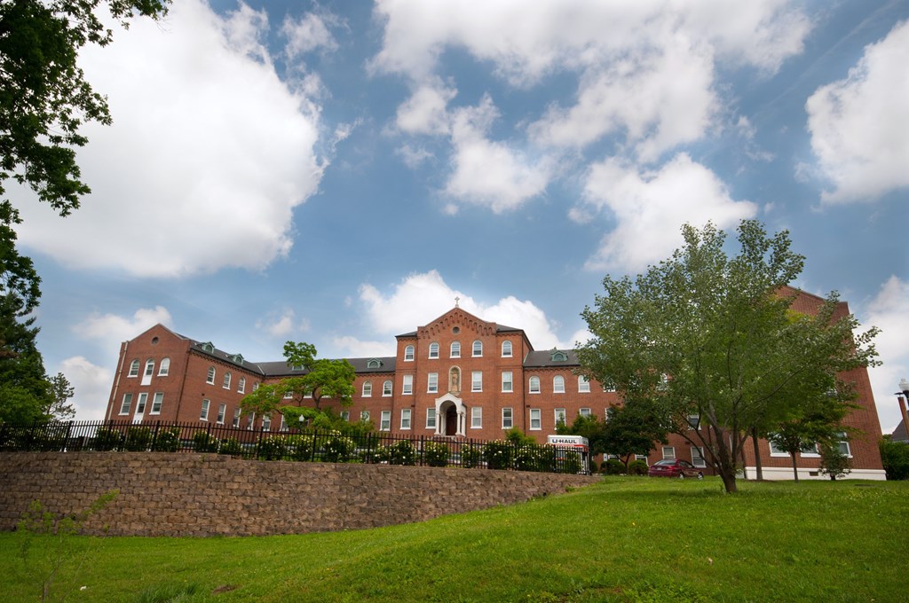 A large red brick building with a green lawn in front.
