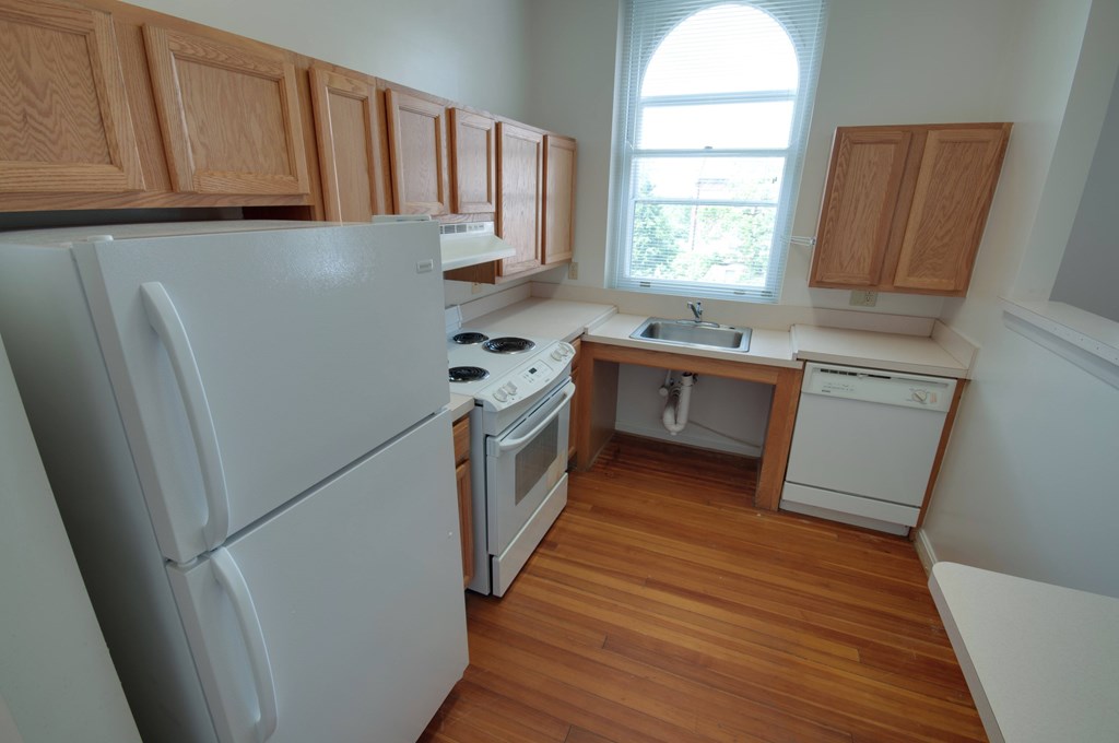 A kitchen with wooden cabinets and a white fridge.