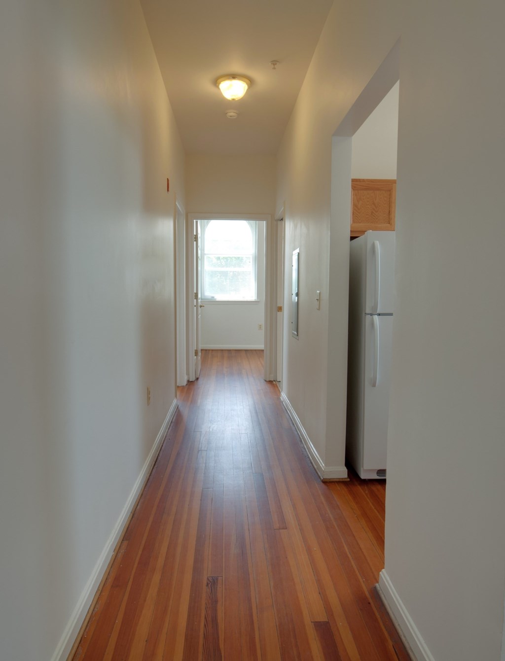 A long hallway with wood floors and white walls.