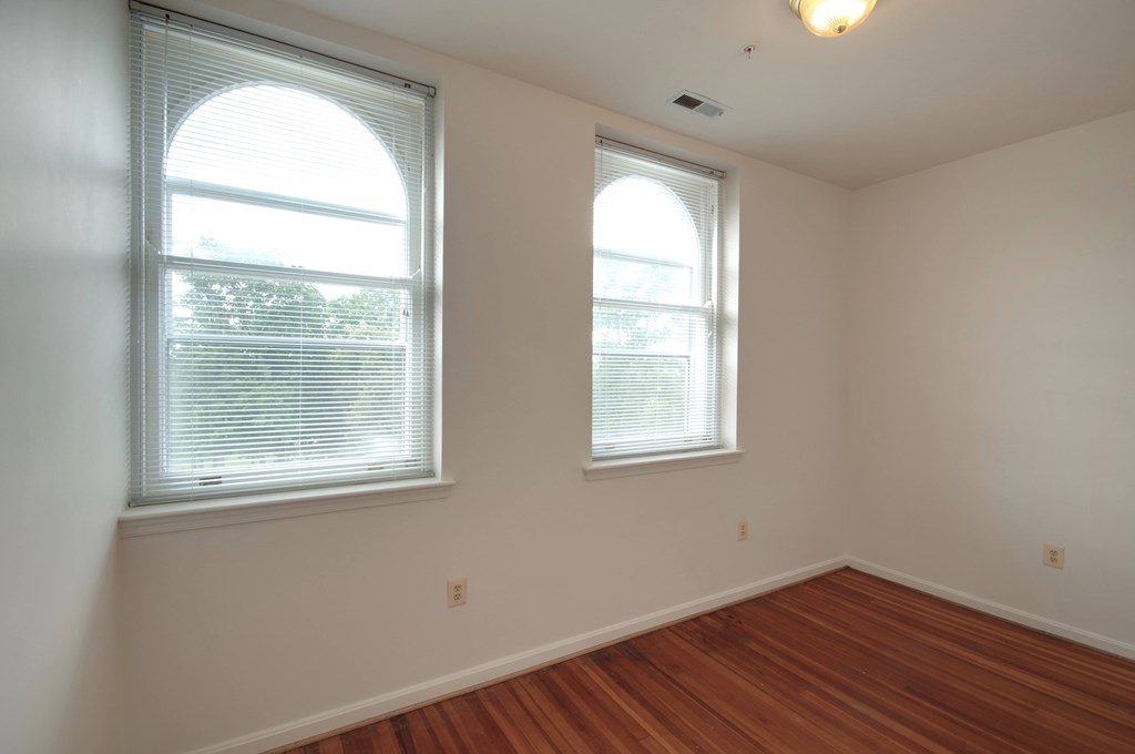 A room with two windows and wooden floors.