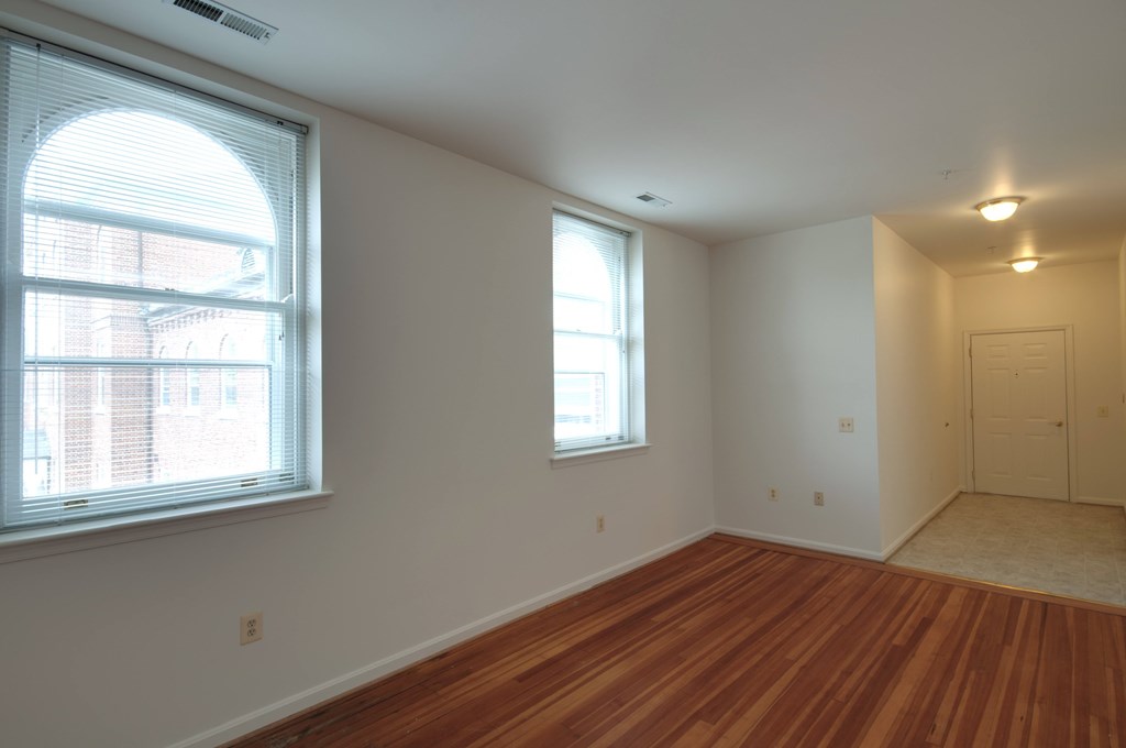 A room with wooden floors and two windows.