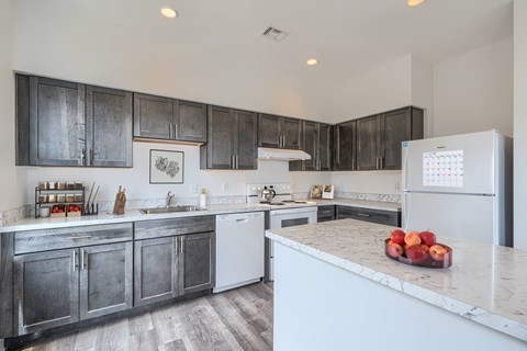 A kitchen with a white fridge and a marble counter top.