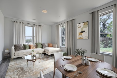A dining room with a table set for two and a couch with pillows.