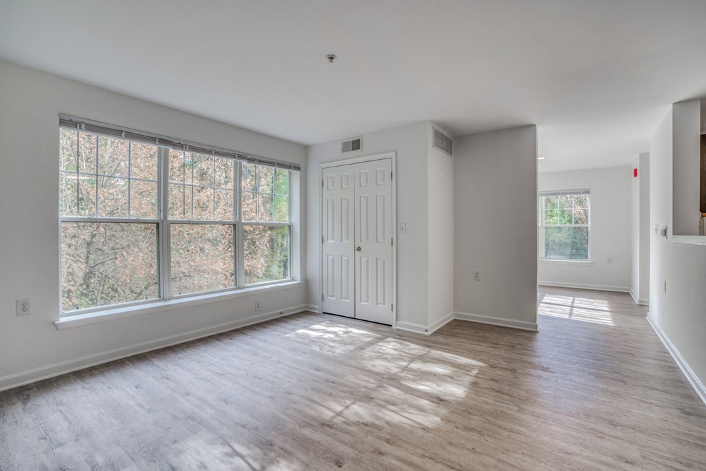 an empty living room with white walls and a large window
