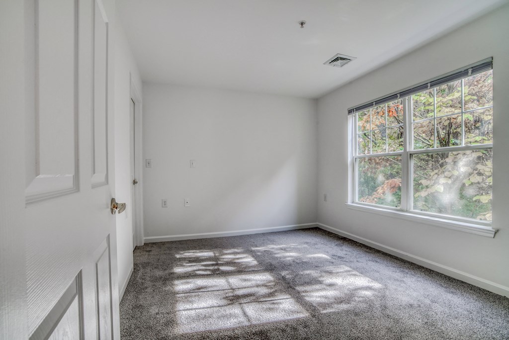 an empty room with white walls and a large window