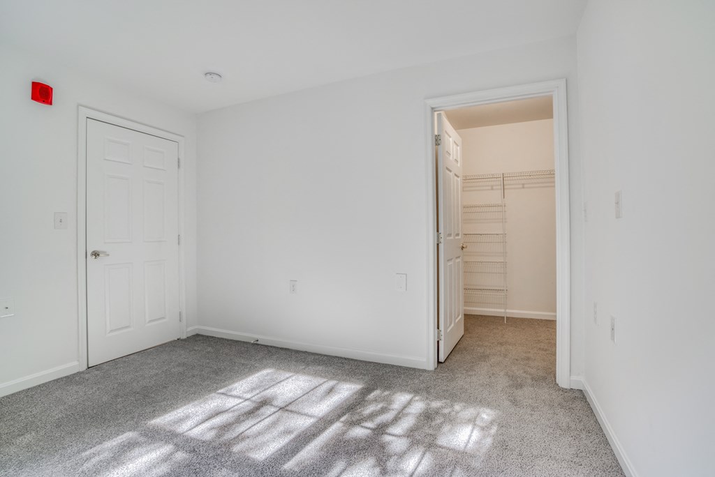 an empty bedroom with a closet and a door to a bathroom