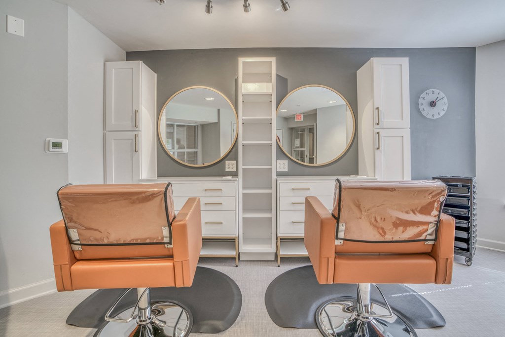 a beauty salon with two orange chairs and mirrors