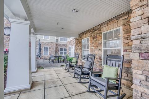 the front porch of a brick house with rocking chairs