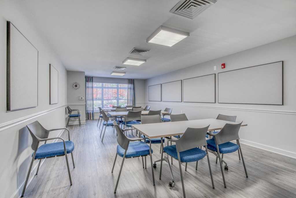 a large classroom with tables and chairs and a projection screen