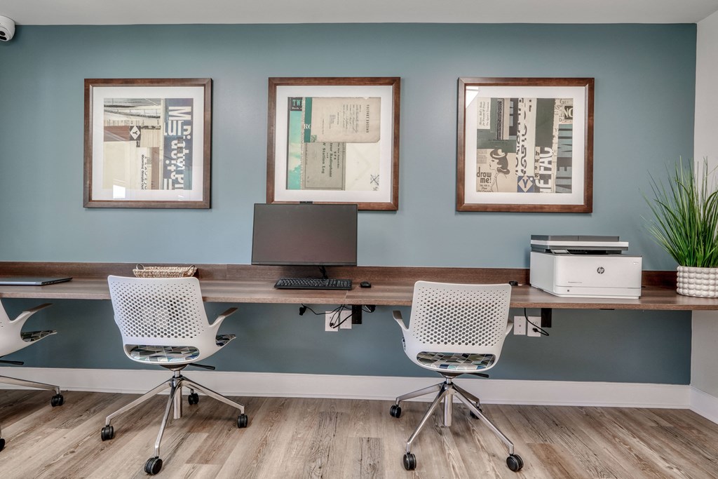 a home office with a desk and three pictures on the wall