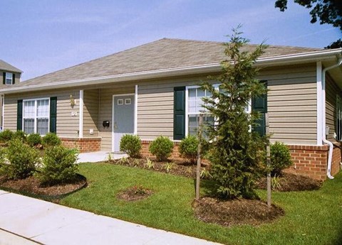 a brown house with a lawn and trees in front of it