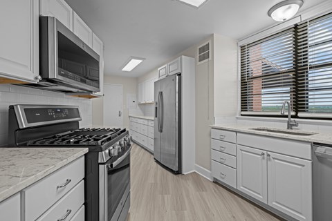A modern kitchen with white cabinets and appliances.