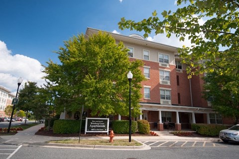 A large brick building with a sign that says "Apartment Community" in front of it.