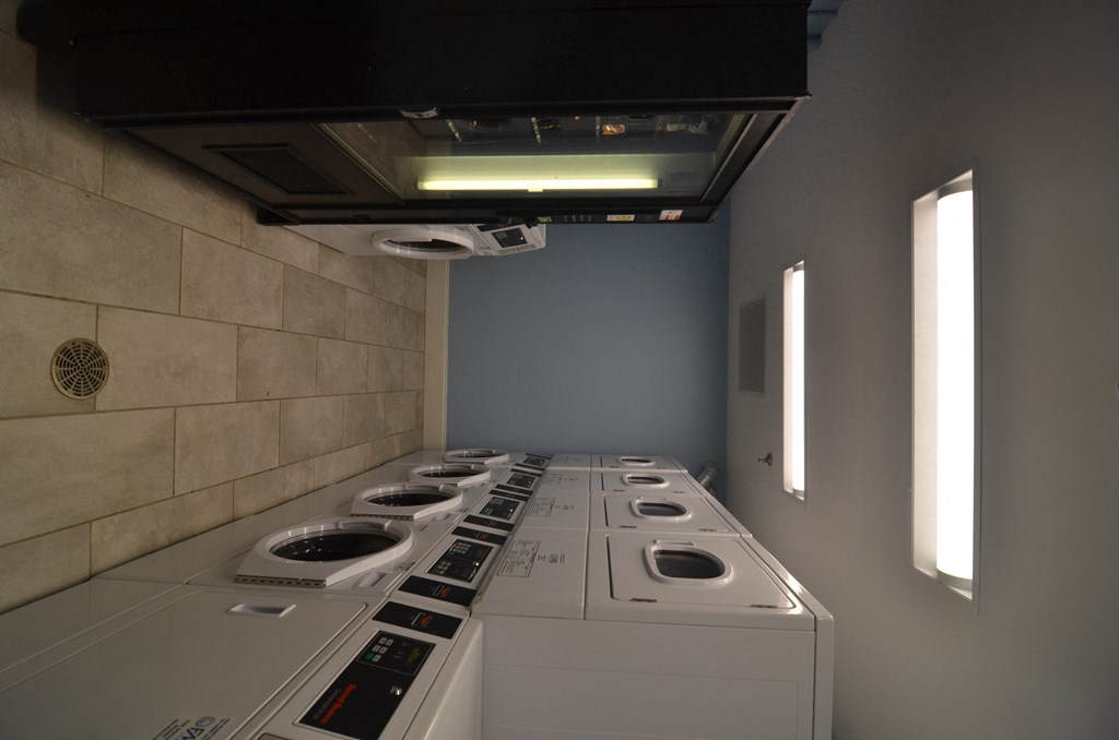 a row of washers and dryers in a laundry room