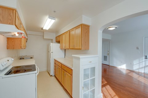 a kitchen with white appliances and wooden cabinets and a door to the living room