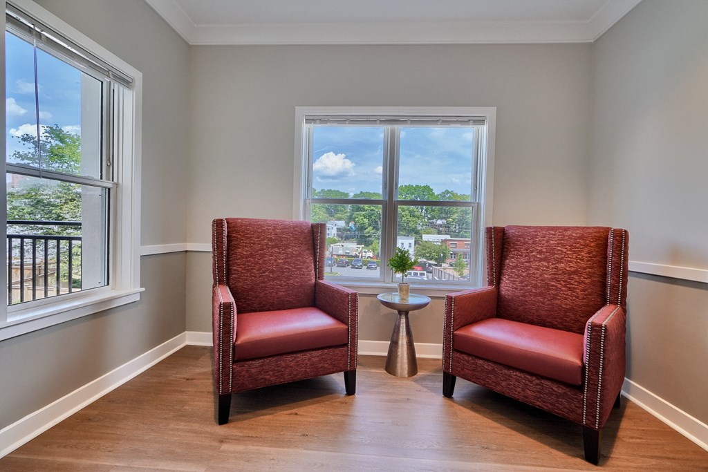 Two red chairs are placed in front of a window.