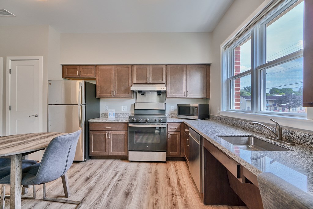 A kitchen with wooden cabinets and a grey chair.