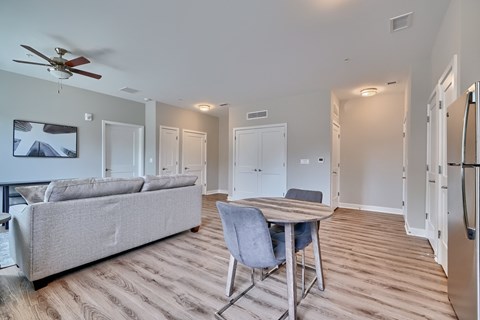 A living room with a grey couch and a wooden dining table.