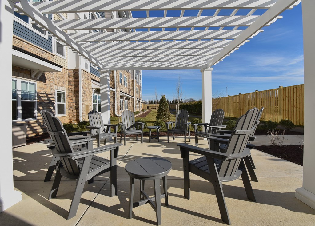 a patio with chairs and tables under a white pergola