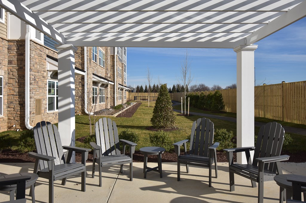 an outdoor patio with chairs and a white pergola