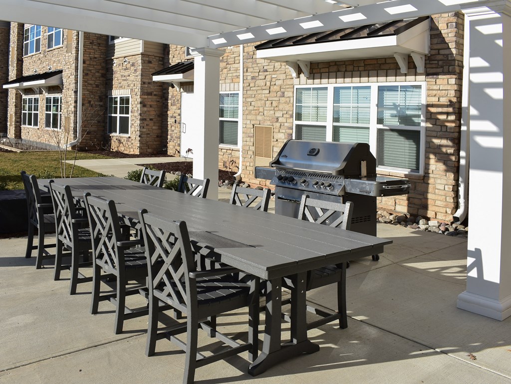 grilling area with chairs under a white pergola
