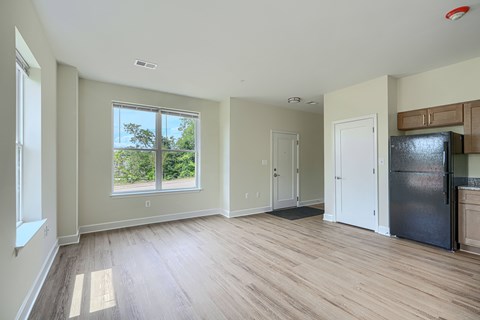 A spacious room with wooden flooring and a large window.