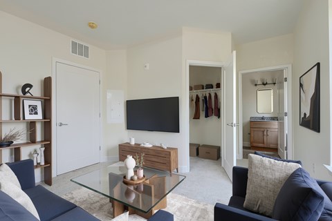 A living room with a blue couch and a glass coffee table.