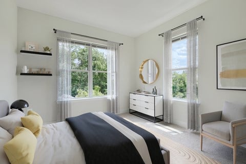 A bedroom with a large bed, a dresser, a chair, and a window with curtains.