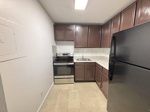 A kitchen with brown cabinets and black appliances.