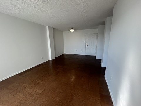 Empty room with wooden flooring and white walls.