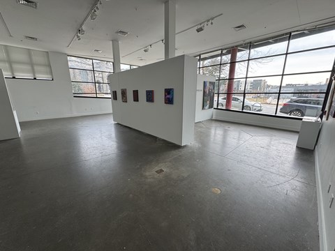 A spacious room with a white wall and a large window.