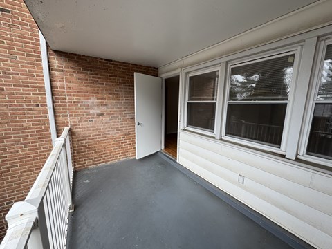 A balcony with a brick wall and a white door.