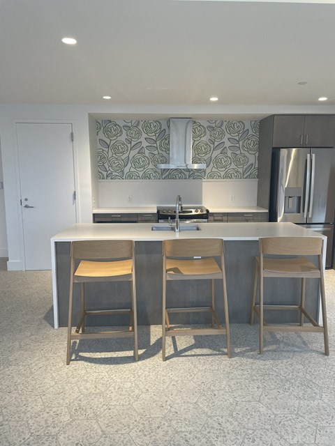 A kitchen with a white counter and bar stools.