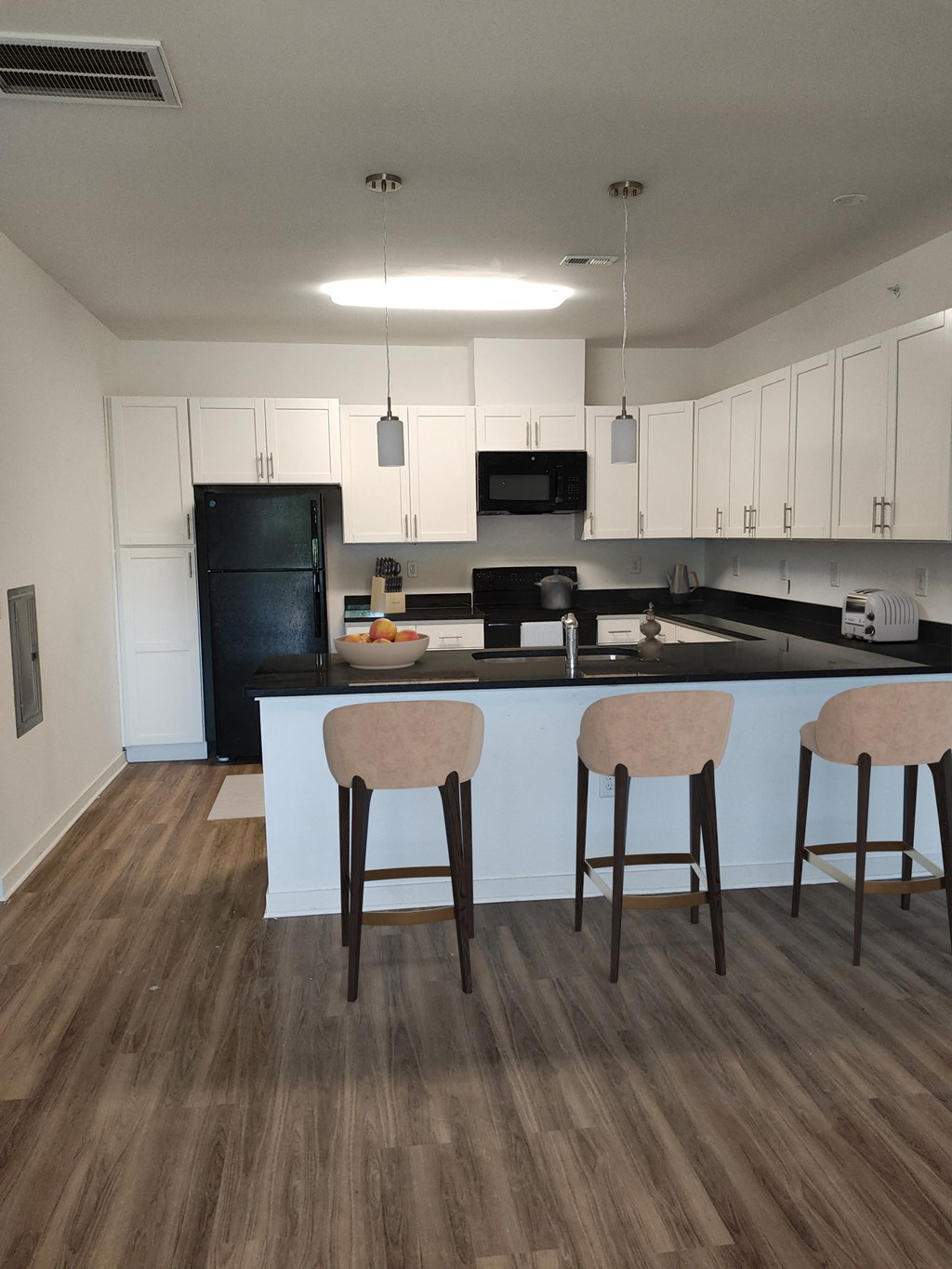 a kitchen with white cabinets and a large island with three stools
