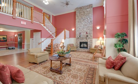 A living room with a stone fireplace and a staircase.
