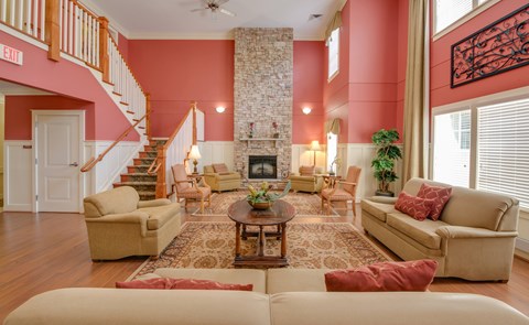 A living room with a stone fireplace and a staircase.