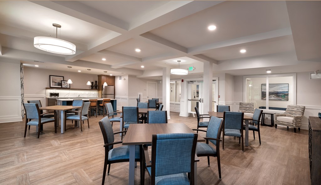 a community room with tables and chairs and a kitchen