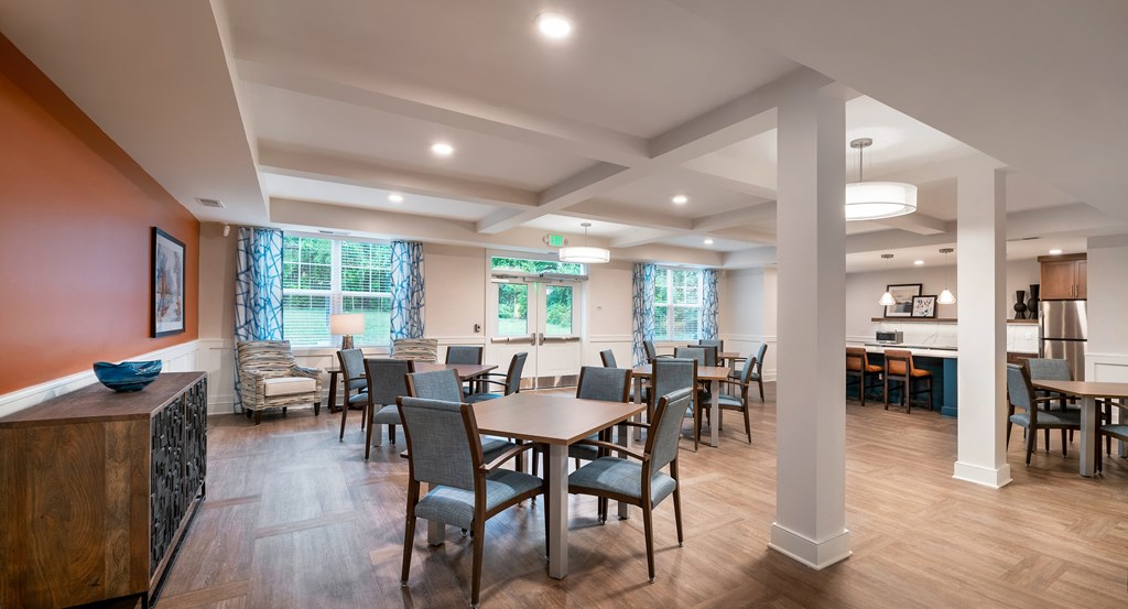 a community room with tables and chairs and a kitchen