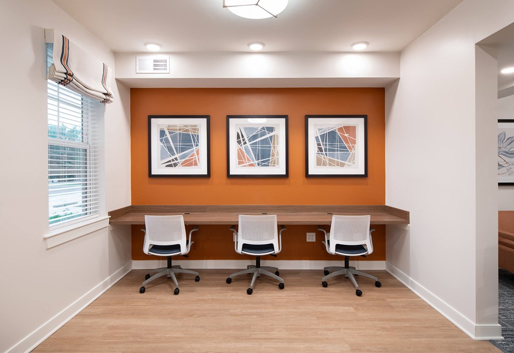 a conference room with four chairs and a desk with three pictures on the wall