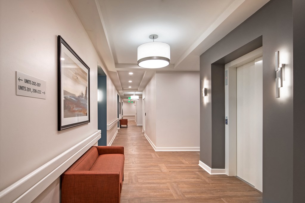 a long hallway with a bench and a painting on the wall and a door