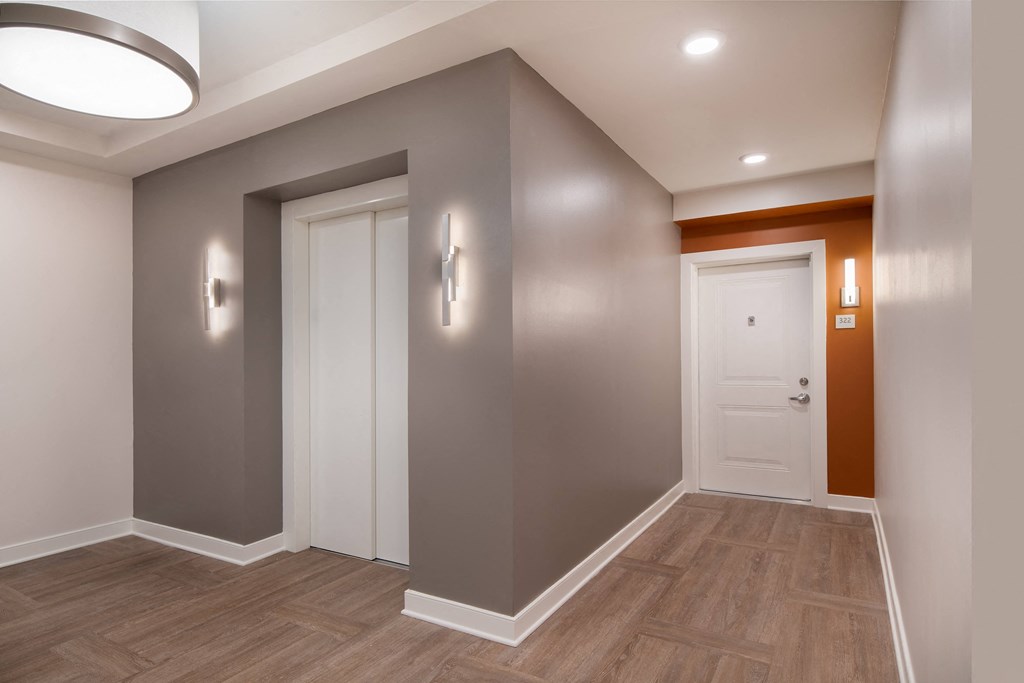 a corridor with a white door and grey walls and a wooden floor