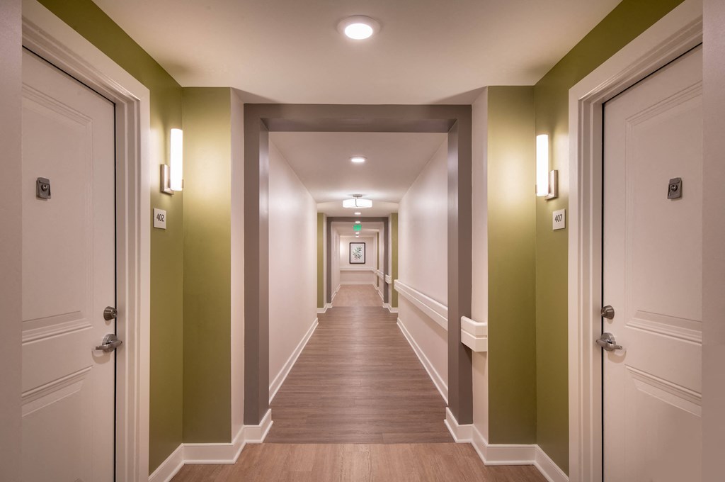 a hallway with green walls and wooden floors and white doors