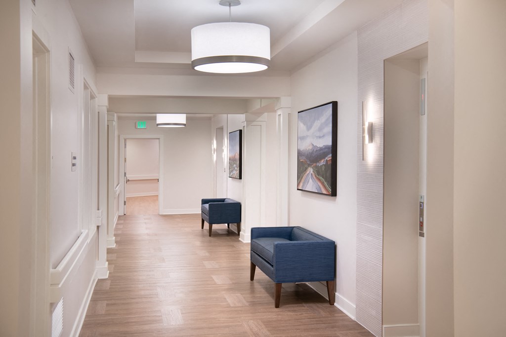 a hallway with blue chairs and white walls and a wood floor